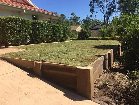 Timber sleeper retaining wall along a paved path below a lawn