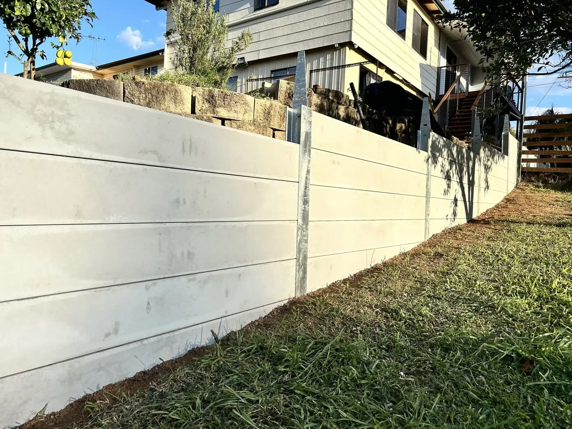 Smooth grey concrete sleeper retaining wall below a raised timber deck