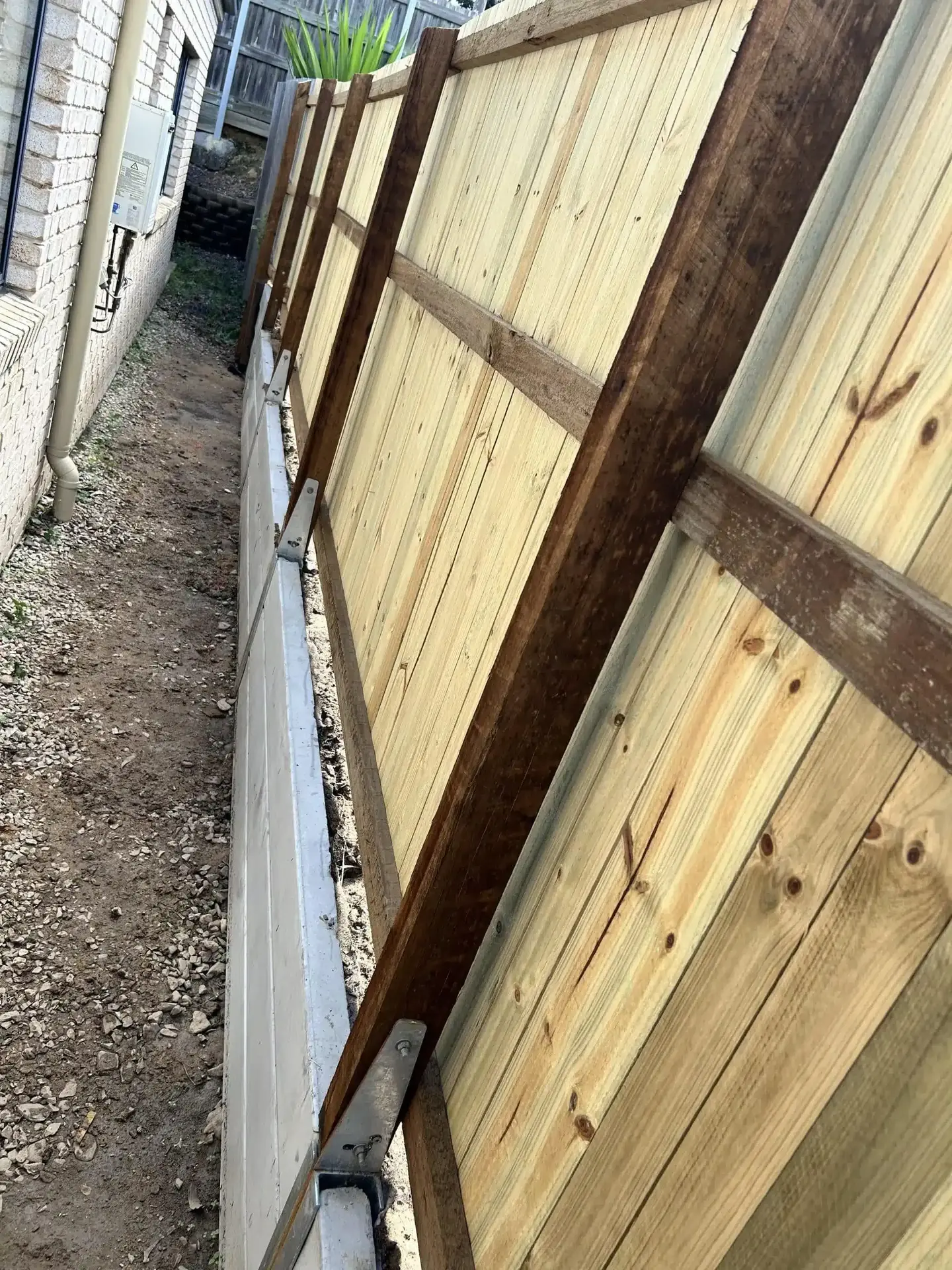 Treated timber retaining wall with timber posts along a narrow side path