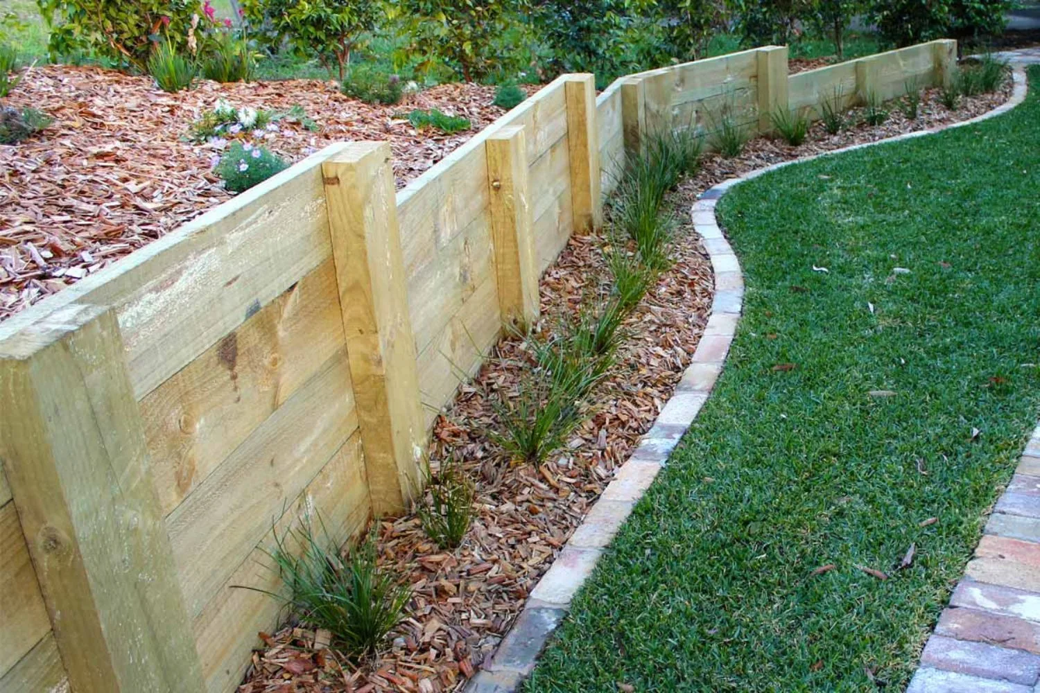 Stepped treated pine retaining wall along a curved lawn edge